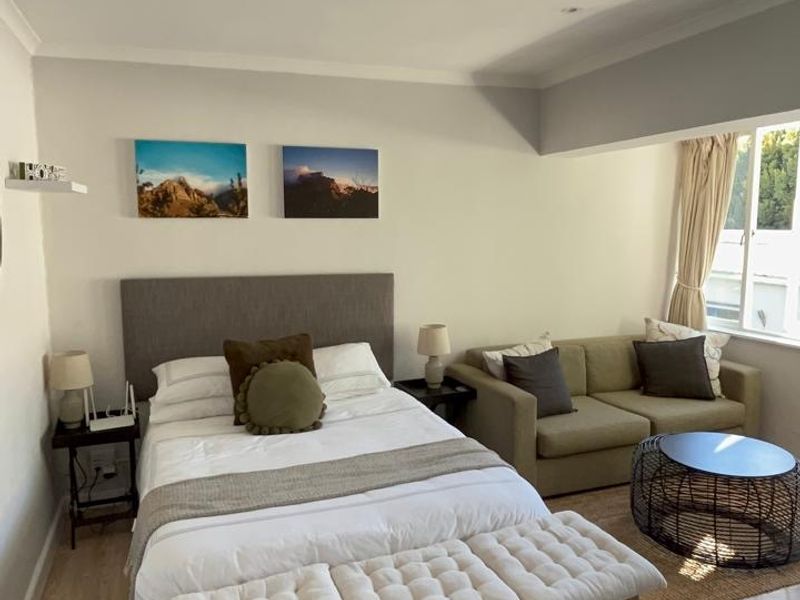 A well-lit bedroom featuring laminate flooring, recessed downlighting, and coving, offering a comfortable and functional living space.