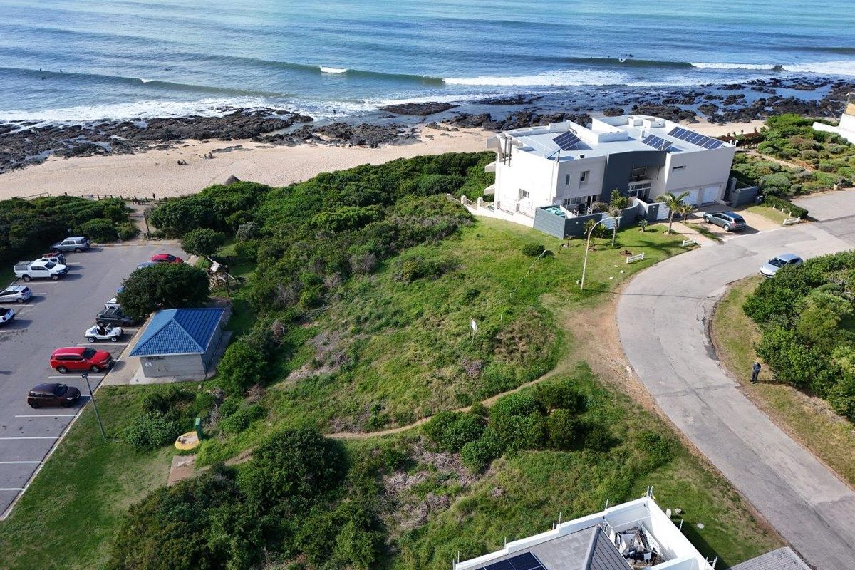 Aerial view of a vacant residential plot situated in a prime coastal location, featuring direct proximity to the beach and established road access.