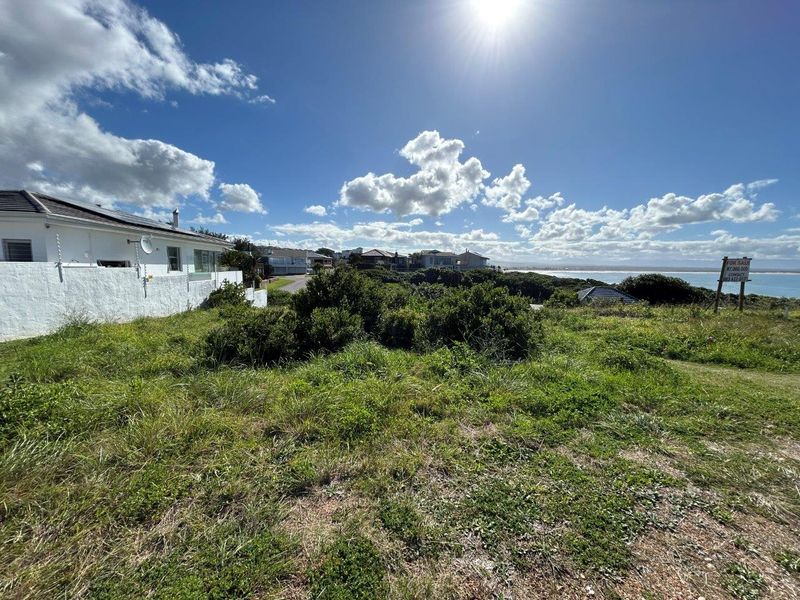 A vacant residential plot featuring coastal vegetation with views of the surrounding neighborhood and nearby ocean.