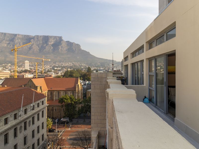A spacious balcony offering expansive urban views of the city and Table Mountain, featuring sliding door access to the interior living space.