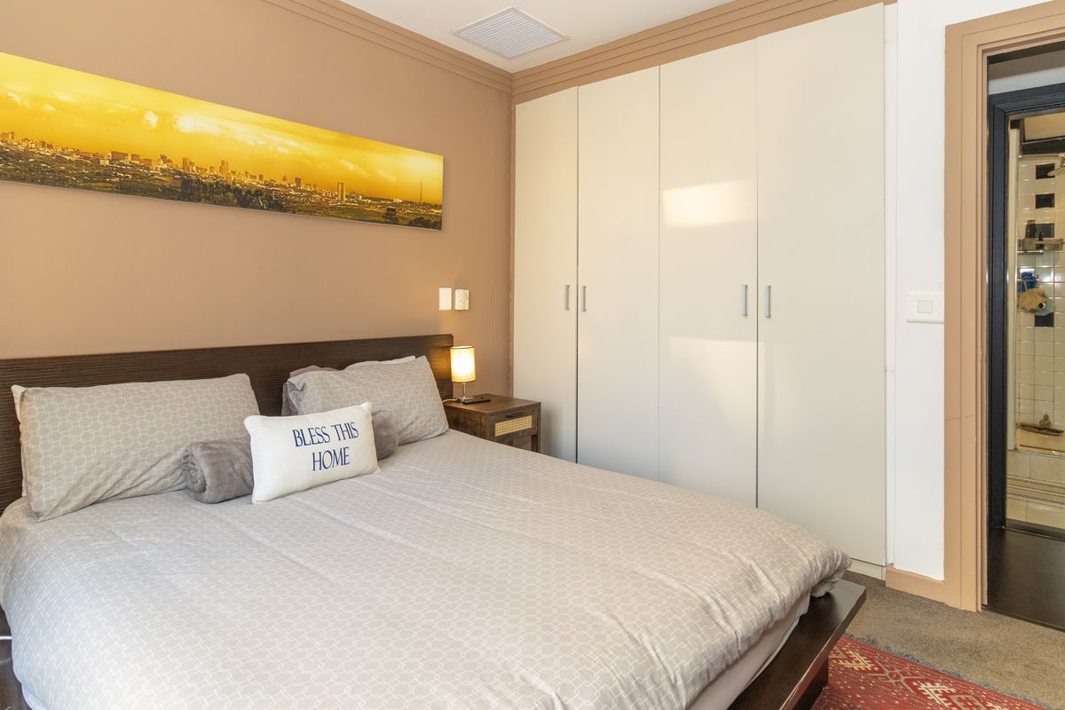 A well-maintained bedroom featuring built-in wardrobes and direct access to an en-suite bathroom, finished with neutral wall tones.