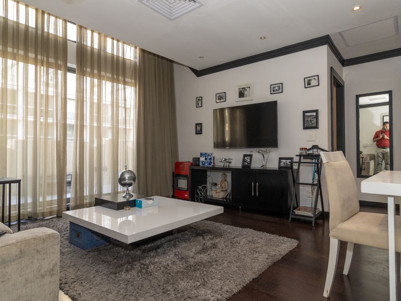 A well-maintained open-plan living and dining area featuring hardwood flooring, recessed lighting, and floor-to-ceiling curtains providing ample natural light.