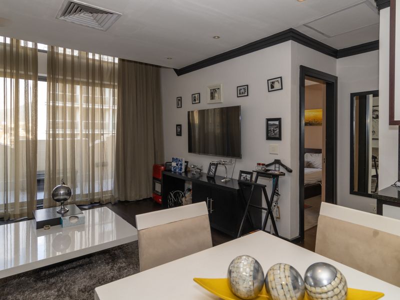 Open-plan living and dining area featuring dark wood flooring, recessed lighting, and direct access to a balcony through large sliding glass doors.