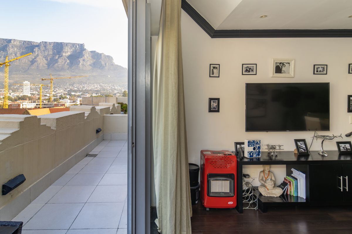 Living room featuring dark wood flooring and direct access to a spacious balcony with panoramic mountain views.