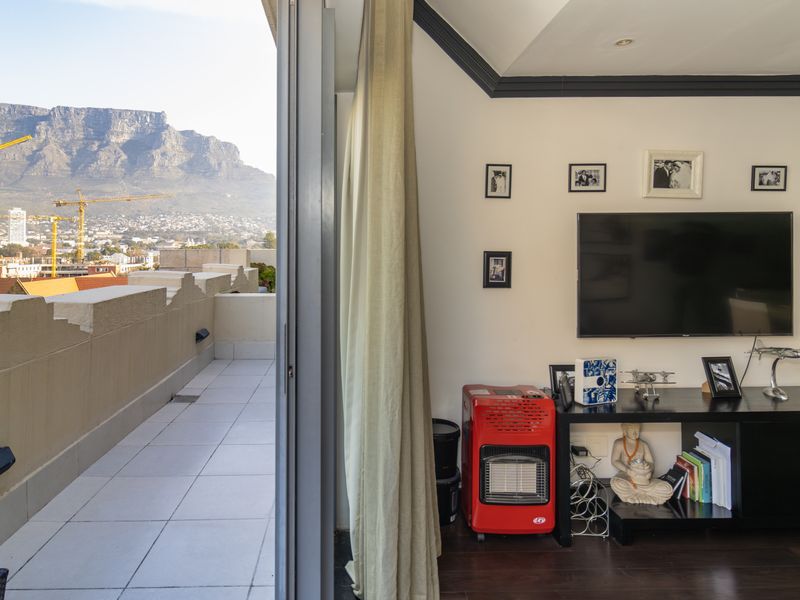 Living room featuring dark wood flooring and direct access to a spacious balcony with panoramic mountain views.