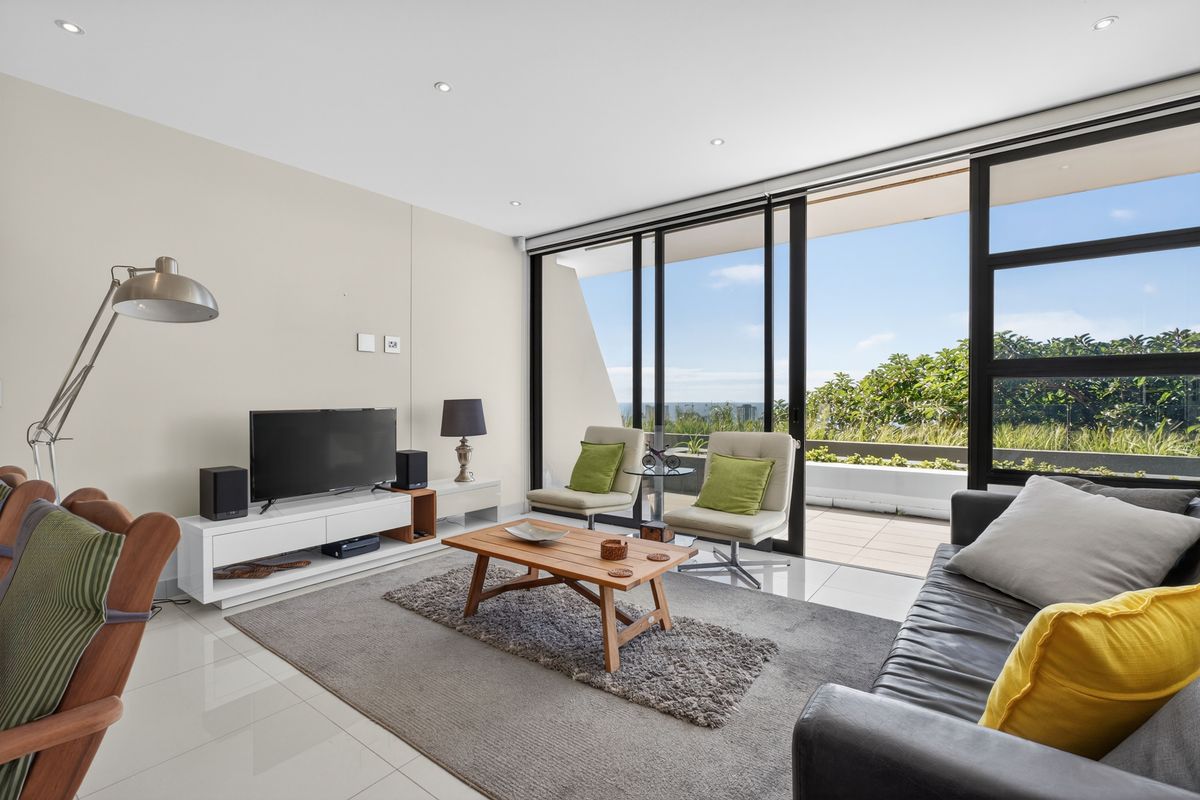 Bright and modern living room featuring large sliding glass doors that open onto a private balcony with scenic views.