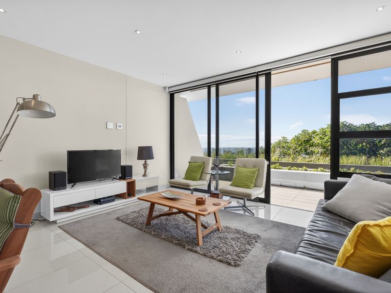 Bright and modern living room featuring large sliding glass doors that open onto a private balcony with scenic views.