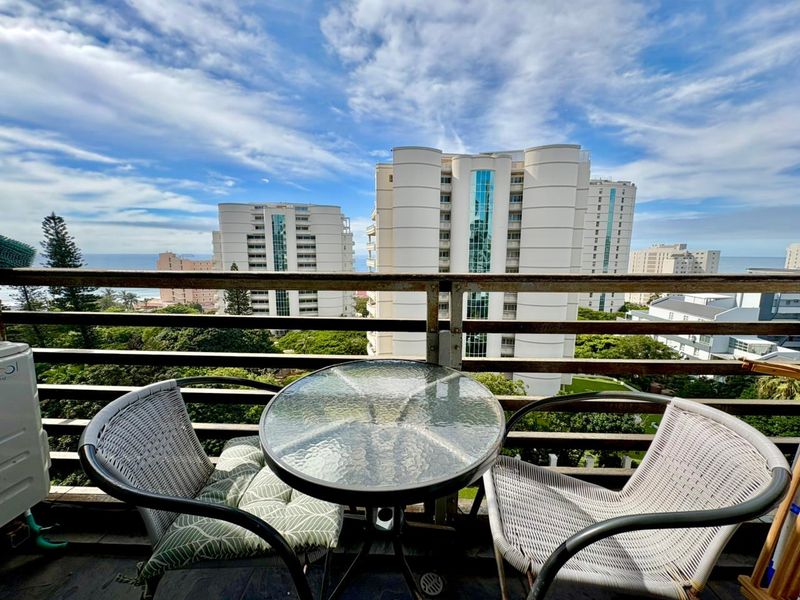 A balcony featuring a metal balustrade with visible signs of corrosion, offering an elevated view of the surrounding apartment buildings.