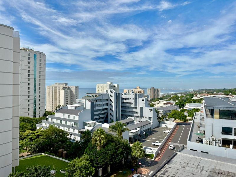 Elevated urban and coastal view overlooking surrounding apartment complexes, local streets, and distant ocean horizon.