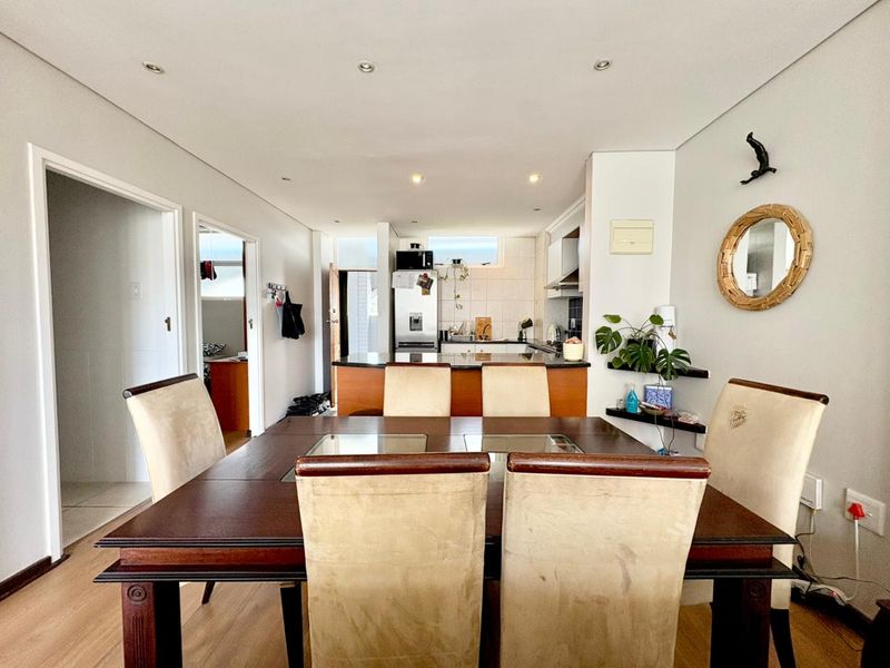 Open-plan dining and kitchen area featuring laminate flooring, recessed lighting, and a functional kitchen layout with granite countertops and tiled backsplash.