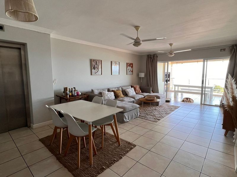 Spacious open-plan living and dining area featuring tiled floors, ceiling fans, and large sliding doors leading to an outdoor balcony.