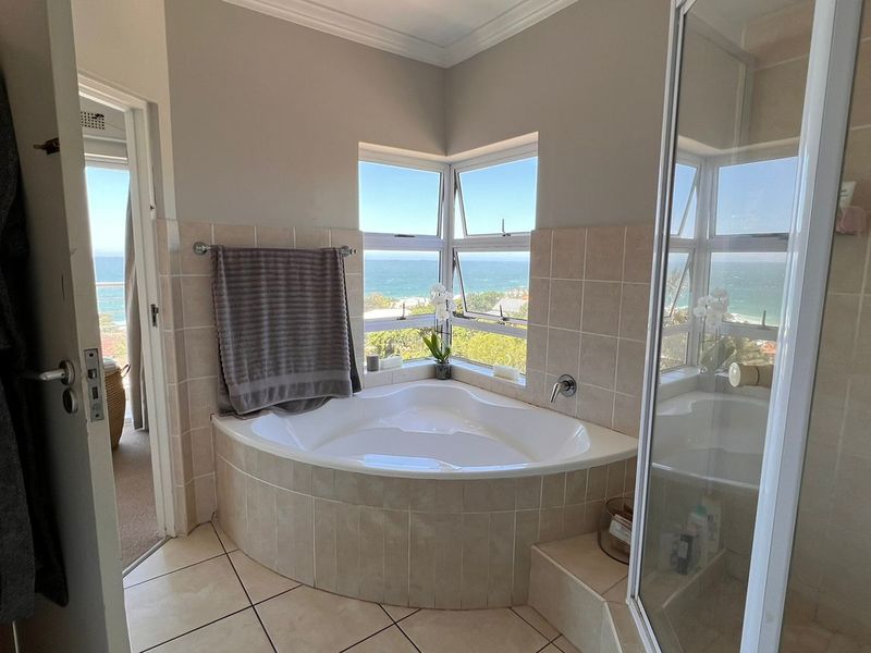 A well-lit bathroom featuring a corner bathtub, separate shower enclosure, and large windows offering scenic ocean views.