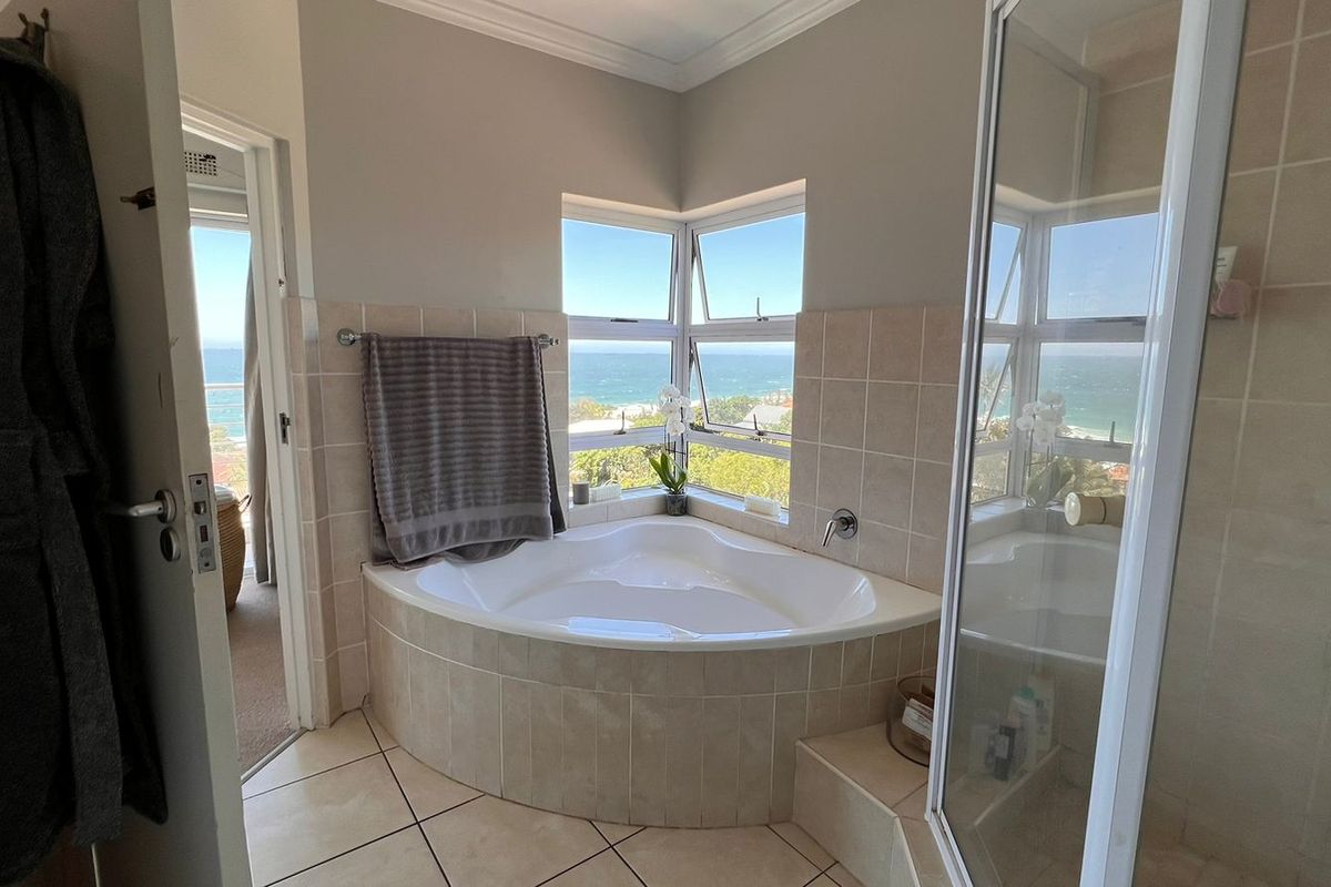 A well-lit bathroom featuring a corner bathtub, separate shower enclosure, and large windows offering scenic ocean views.