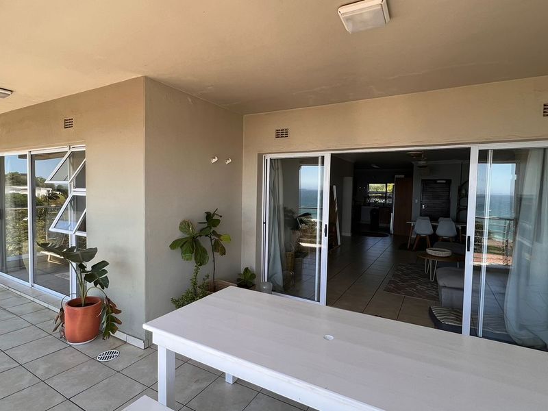 A spacious covered balcony featuring tiled flooring and large sliding glass doors that provide seamless access to the interior living area.