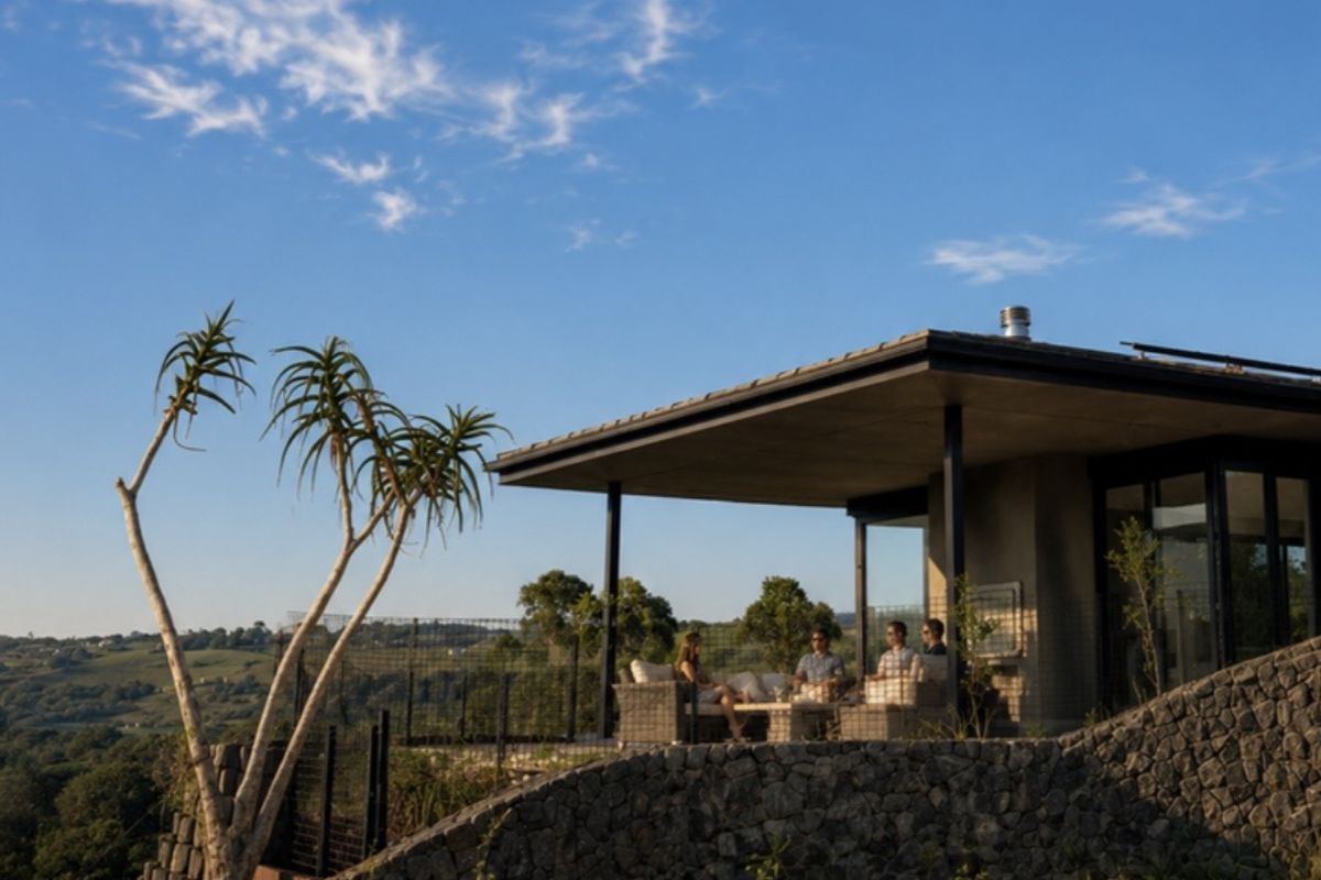 A modern covered patio featuring a stone retaining wall, concrete roof structure, and expansive views of the surrounding landscape.