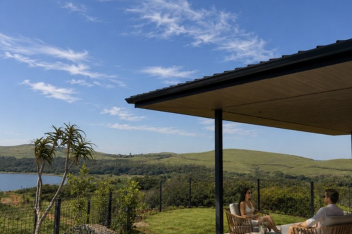 A modern covered patio area overlooking a swimming pool with expansive views of the surrounding landscape and lake.