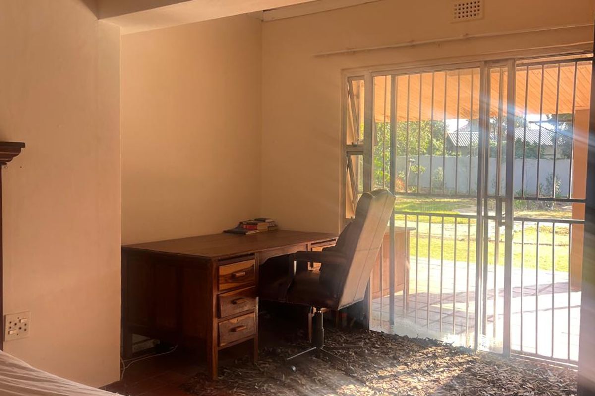 A bedroom featuring tiled flooring and a sliding glass door with a security gate, providing direct access to the outdoor area.