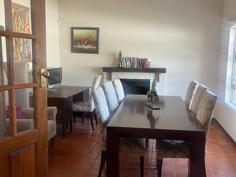 Dining room featuring terracotta floor tiles, a fireplace with a mantelpiece, and decorative ceiling rose, providing a traditional and functional living space.