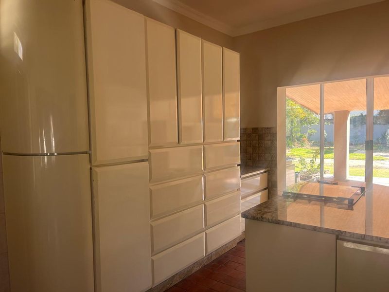 Kitchen featuring extensive built-in cabinetry, granite countertops, and an integrated cooktop, with direct access to an outdoor patio area.