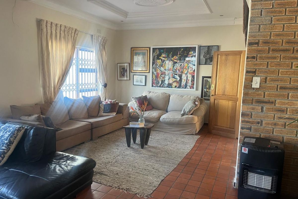 A cozy living room featuring terracotta floor tiles, an exposed brick fireplace, and decorative ceiling molding, offering a warm and traditional atmosphere.