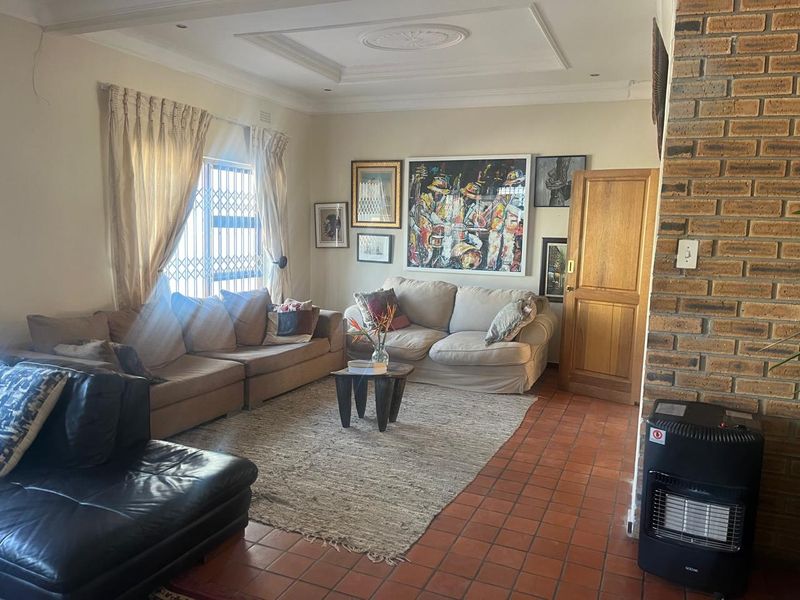A cozy living room featuring terracotta floor tiles, an exposed brick fireplace, and decorative ceiling molding, offering a warm and traditional atmosphere.