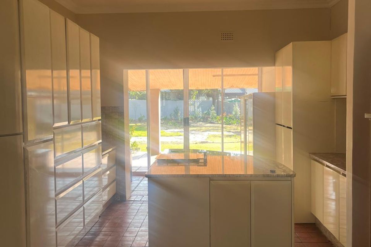 Spacious kitchen featuring built-in cabinetry, a central island, and tiled flooring, with direct access to the outdoor patio area through sliding glass doors.