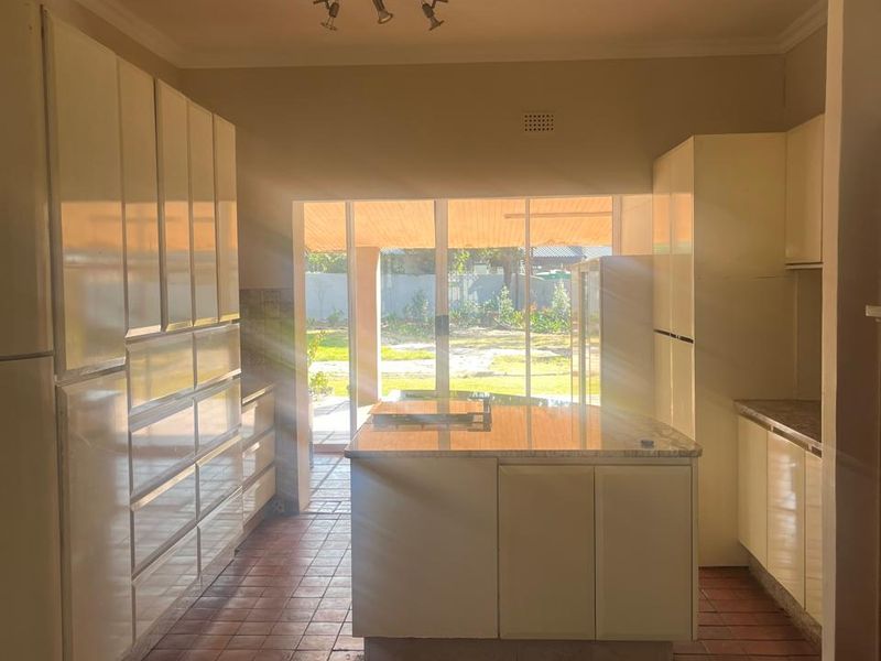 Spacious kitchen featuring built-in cabinetry, a central island, and tiled flooring, with direct access to the outdoor patio area through sliding glass doors.