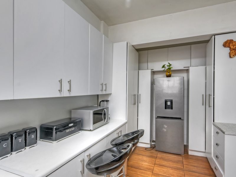 A functional kitchen featuring white built-in cabinetry, laminate countertops, and tiled flooring, providing ample storage and workspace.
