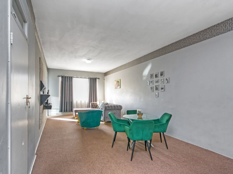 Open plan living and dining area featuring carpeted flooring and a decorative wallpaper border, offering a functional space for relaxation and meals.