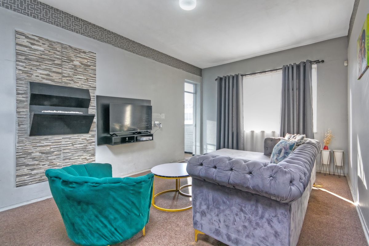 A comfortable living room featuring a modern wall-mounted fireplace with decorative stone cladding and a neutral color palette.