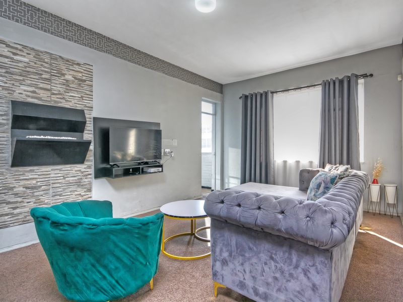 A comfortable living room featuring a modern wall-mounted fireplace with decorative stone cladding and a neutral color palette.