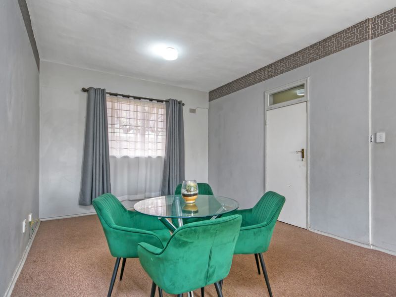 A dining area featuring carpet flooring and a transom window above the door, with neutral wall finishes.