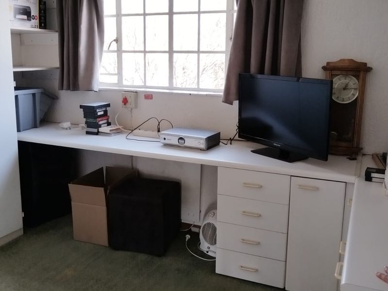 A functional home office space featuring a built-in desk, integrated cabinetry, and shelving, providing a practical workspace with natural light.
