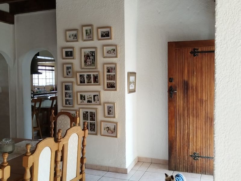 Living area featuring exposed timber ceiling beams, tiled flooring with a decorative border, and a classic solid timber door with arched architectural detailing.