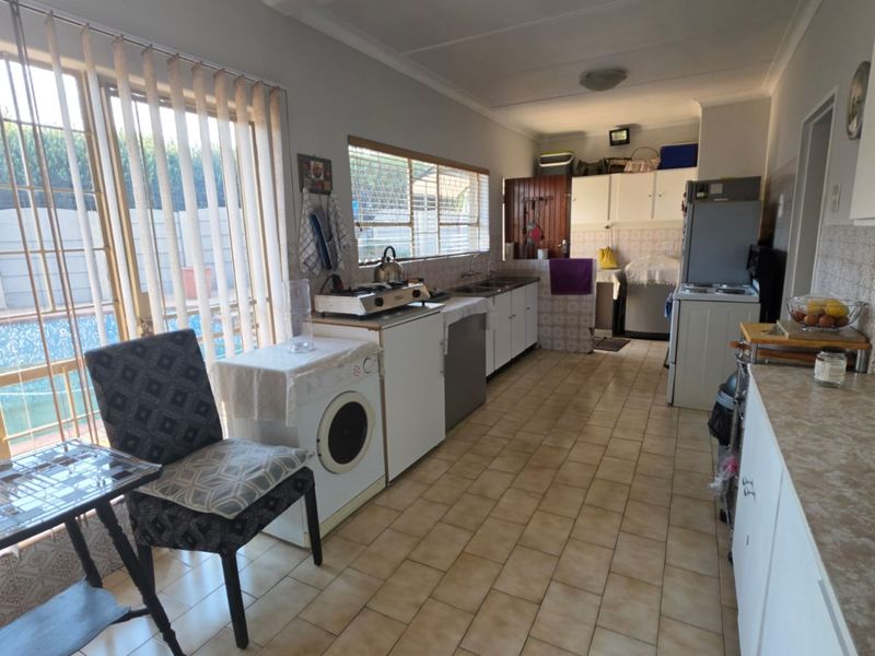 A functional kitchen featuring tiled flooring, built-in cabinetry, and laminate countertops, with direct access to the outdoor pool area through sliding glass doors.