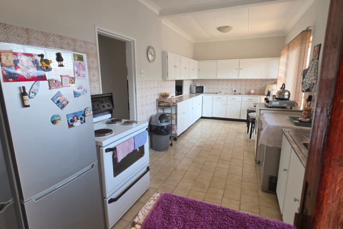 A functional kitchen featuring extensive built-in cabinetry, tiled flooring, and a tiled backsplash, offering a practical layout with ample storage space.