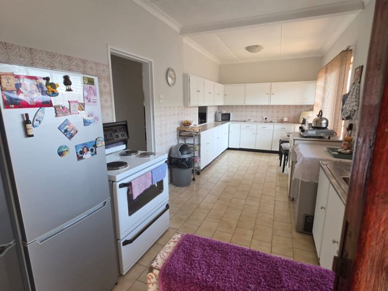 A functional kitchen featuring extensive built-in cabinetry, tiled flooring, and a tiled backsplash, offering a practical layout with ample storage space.