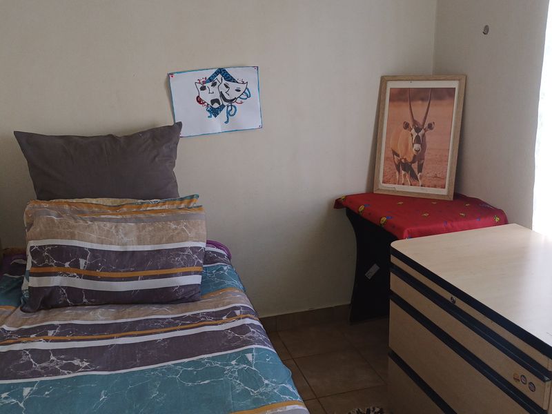 A compact bedroom featuring tiled flooring and neutral wall finishes, suitable for a single bed setup.