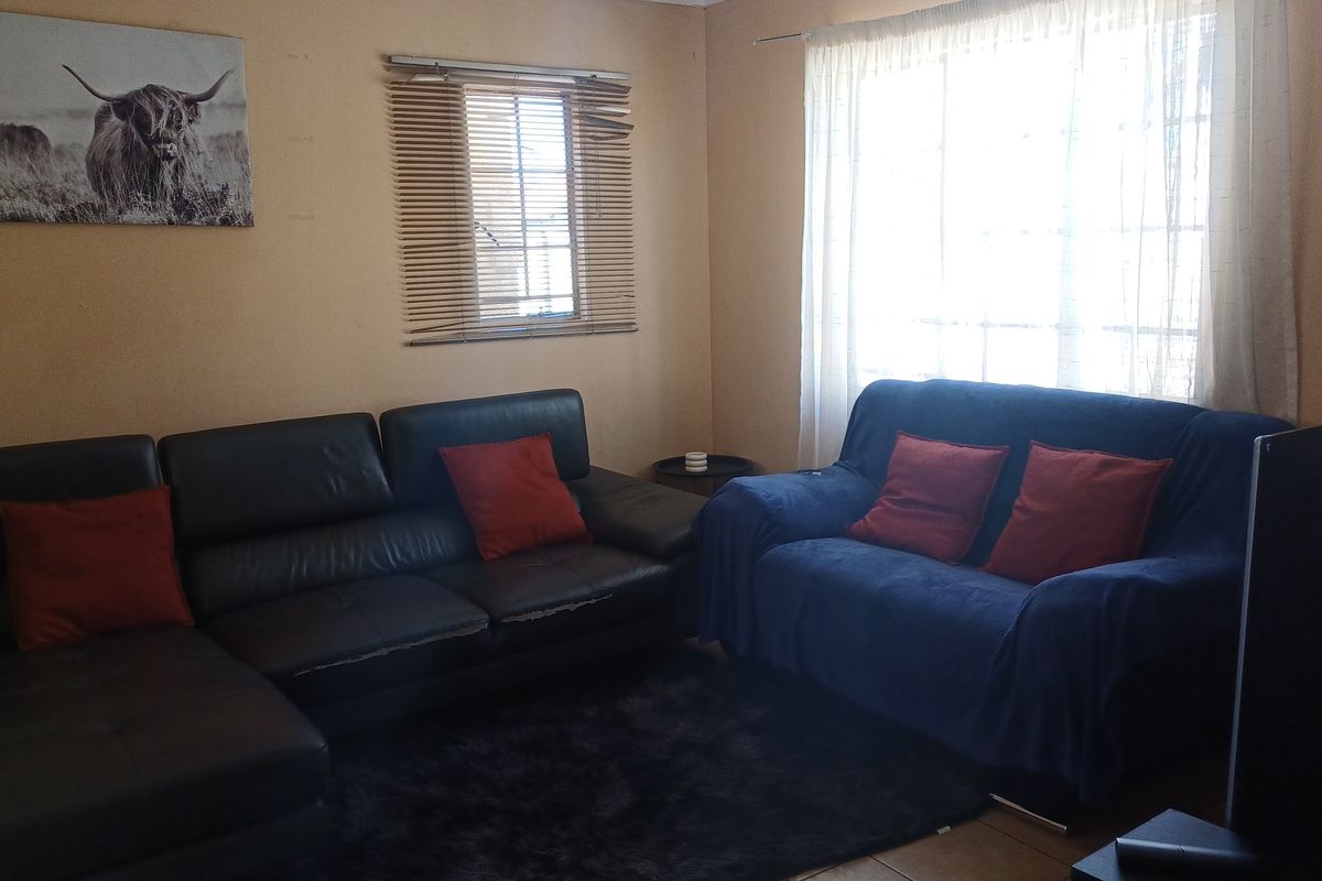 A living room featuring tiled flooring, window blinds, and curtain rails. The space requires cosmetic updates to improve its overall condition and appeal.