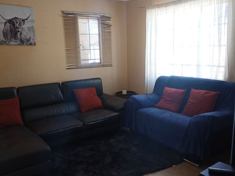 A living room featuring tiled flooring, window blinds, and curtain rails. The space requires cosmetic updates to improve its overall condition and appeal.
