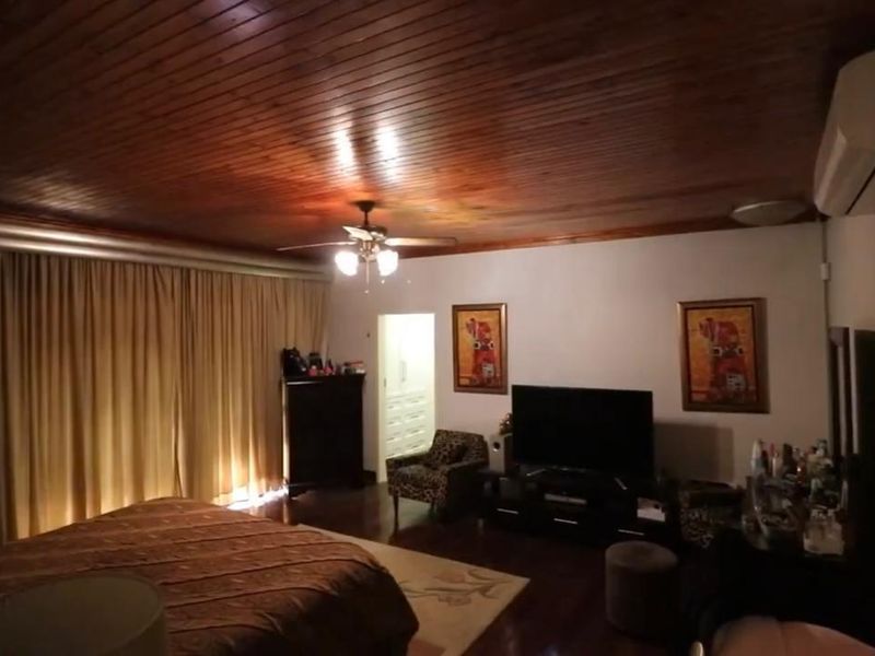 Spacious bedroom featuring a warm timber-clad ceiling, ceiling fan, and a wall-mounted split-system air conditioning unit.