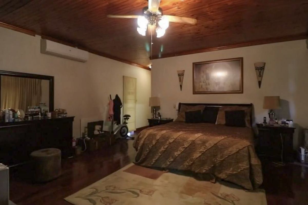 Spacious bedroom featuring a warm timber ceiling, hardwood flooring, and a wall-mounted split-system air conditioner for climate control.
