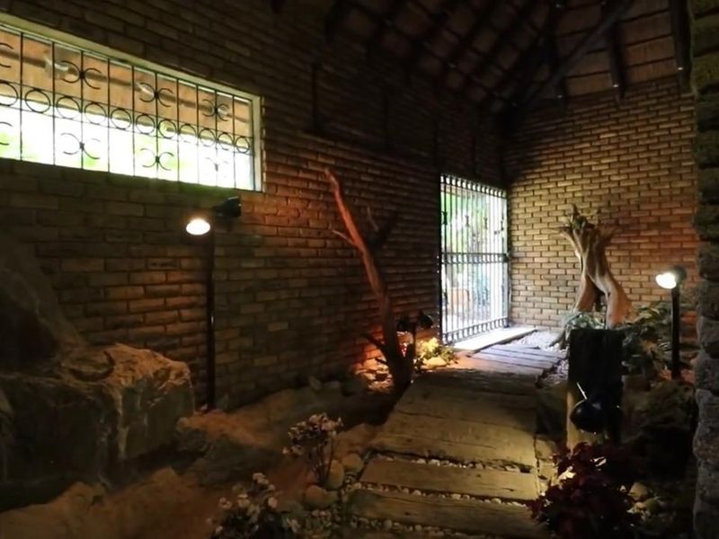 A rustic, enclosed patio area featuring exposed brick walls, a timber ceiling, and a decorative stone-lined walkway with integrated lighting.