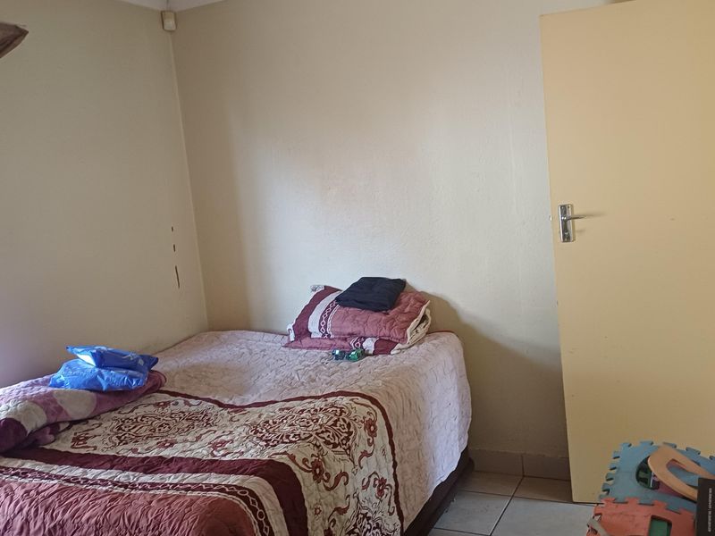 A compact bedroom featuring tiled flooring and a standard internal door, requiring minor cosmetic updates to the wall surfaces.