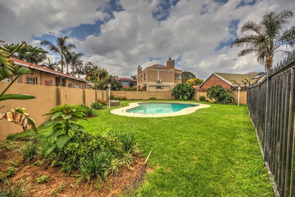 A private backyard featuring a swimming pool, well-maintained lawn, and secure perimeter fencing, providing a functional outdoor space for the townhouse.
