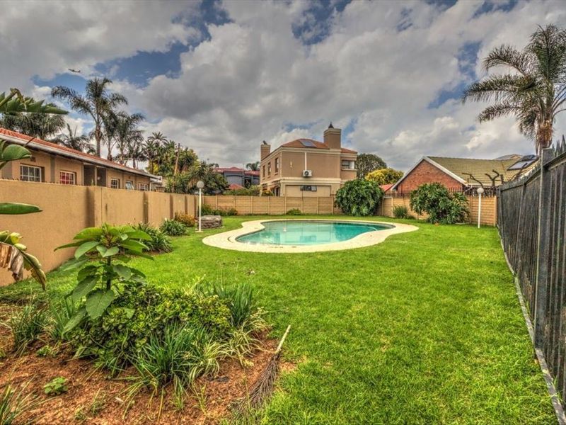 A private backyard featuring a swimming pool, well-maintained lawn, and secure perimeter fencing, providing a functional outdoor space for the townhouse.