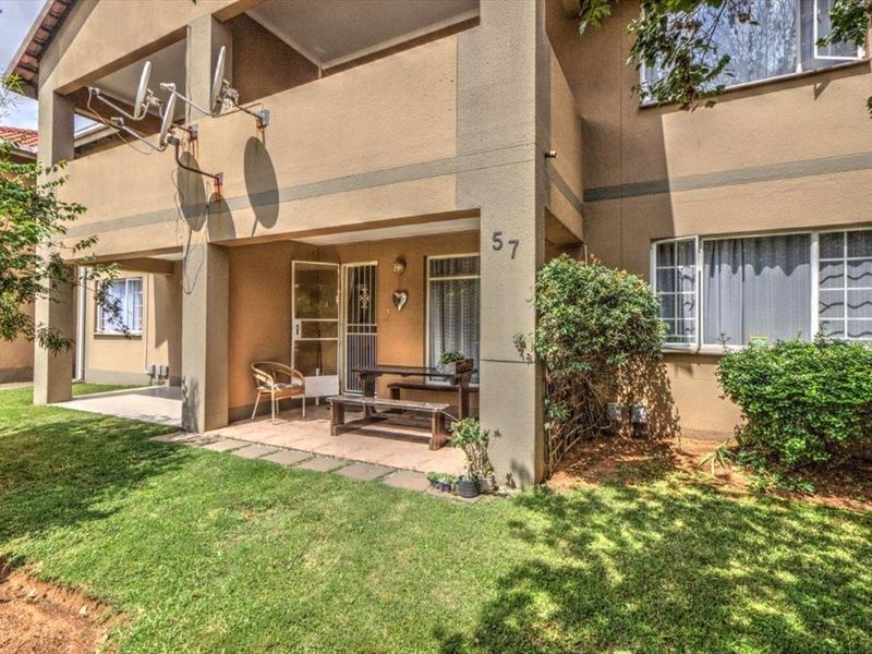 Front elevation of a townhouse featuring a covered patio, tiled flooring, and a small private garden area.