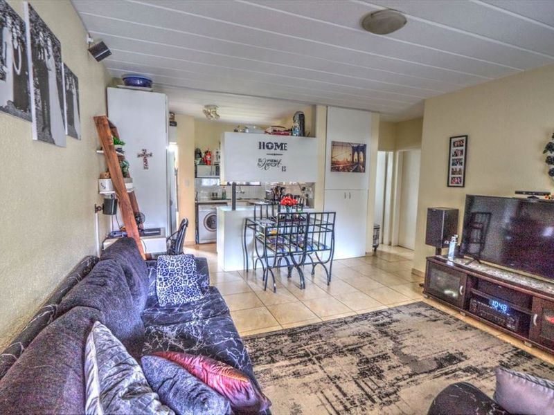 Open plan living and kitchen area featuring tiled flooring and functional built-in cabinetry, offering a versatile space for daily living and dining.