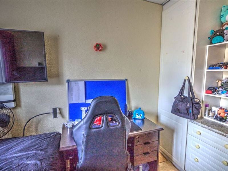 A bedroom featuring a built-in wardrobe and wall-mounted television bracket, offering functional storage and space for a desk setup.