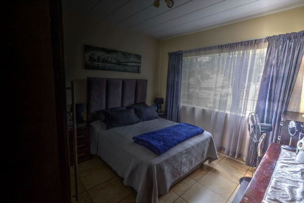 A bedroom featuring tiled flooring and large windows with curtain rails, providing natural light and a functional layout.